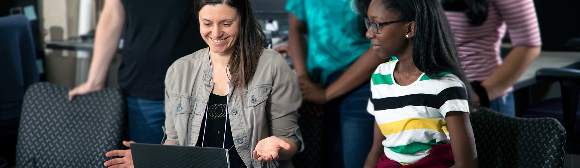 A UAlbany faculty member working with a group of students on laptop.