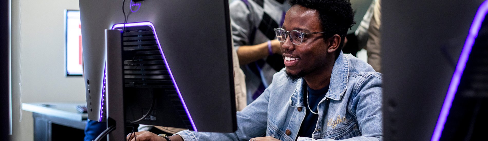 A student working on a large gaming computer monitor.