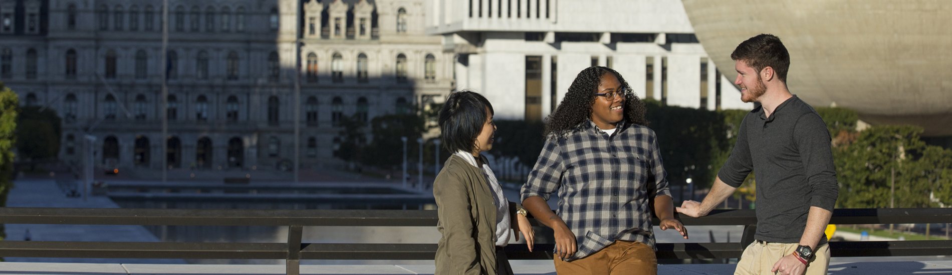 Three students having a conversation on the Empire State Plaza in downtown Albany.