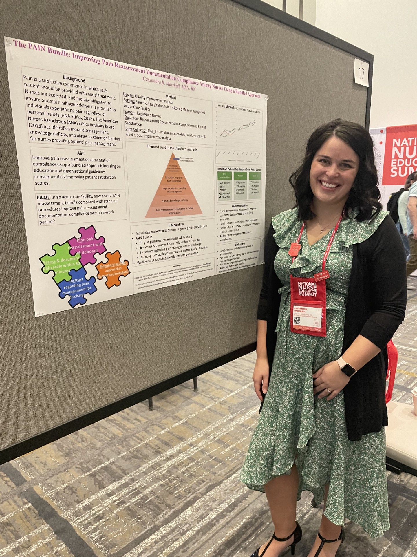 Marshall, wearing a green sundress and black cardigan, stands beside her poster at the National Nurse Education Summit. Her poster is titled “The PAIN Bundle: Improving Pain reassessment Documentation Compliance Among Nurses Using a Bundled Approach.” The poster is tacked to a gray display board. 
